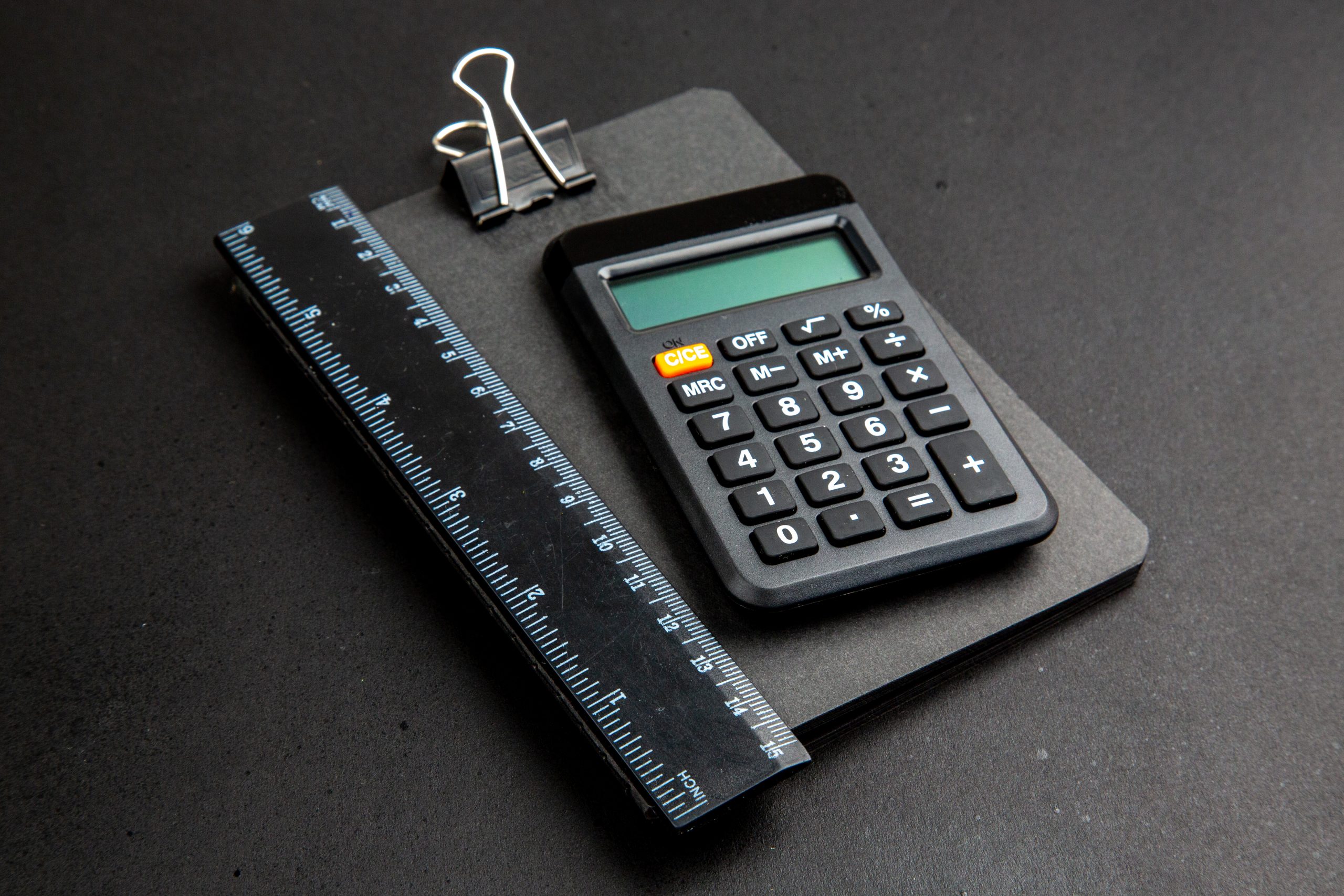 calculadora de vista inferior e régua no bloco de notas na mesa escura