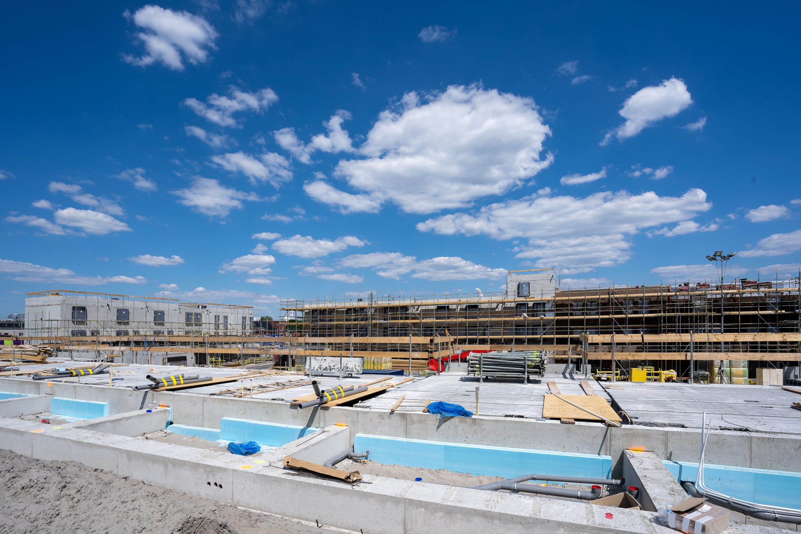 A horizontal shot of a construction site with scaffolding under the clear blue sky